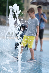 Children play with water in a fountain on a hot day