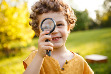 Young blonde boy playing with magnifier