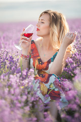 Portrait of beautiful sexy woman is drinking red wine in lavender field