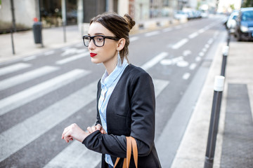 Young businesswoman catching a taxi standing on the street at the modern residential district