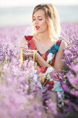 Portrait of beautiful sexy girl is drinking wine in lavender field