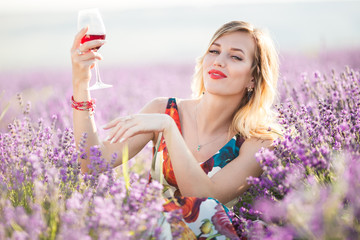 Portrait of beautiful sexy girl is drinking wine in lavender field