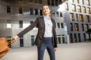 Lifestyle portrait of a young businesswoman swinging bag outdoors at the modern residential district