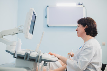 Doctor using ultrasound and screening stomach of pregnant woman.