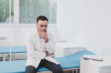 Thoughtful doctor sitting in a operating room with his hand on head