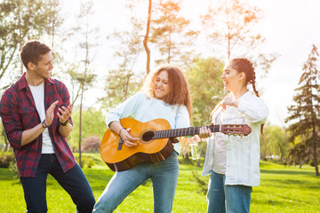 Friends having fun in park with guitar