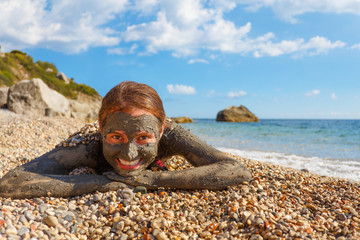 Beauty and Health. Spa Outdoor. Smile face of beautiful Woman smeared mud mask on body, beach Dead Sea. Recreation tourism, healthy lifestyle, body care, natural therapy. Clay body mask. 
