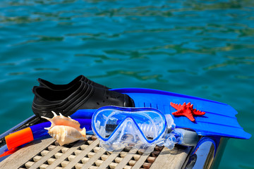 Mask, fins, underwater camera, seashells on the sea background.