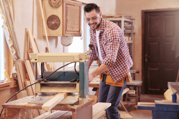 Fototapeta na wymiar Carpenter working with grinder in shop
