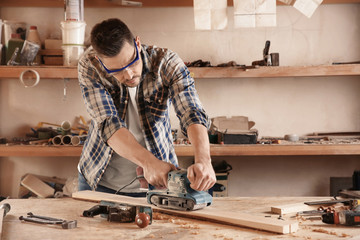 Carpenter working with electric sander in shop