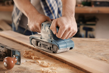 Carpenter working with electric sander in shop