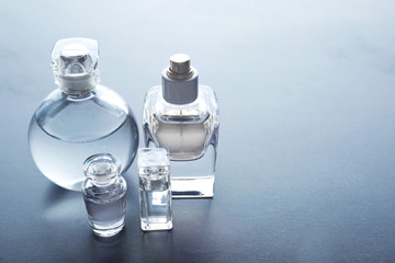 Different perfume bottles on grey background - obrazy, fototapety, plakaty
