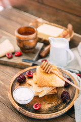 Fresh homemade crepes with honey and berries over rustic background