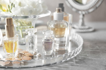 Obraz na płótnie Canvas Glass tray with perfume bottles on grey table