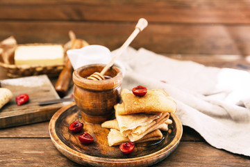 Fresh homemade crepes with honey and berries over rustic background