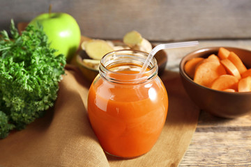 Jar of carrot juice on wooden table