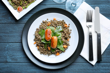Composition with tasty lentil porridge, sausages and vegetables on wooden table