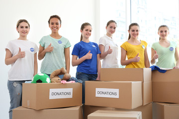 Young volunteers with boxes of donations indoors