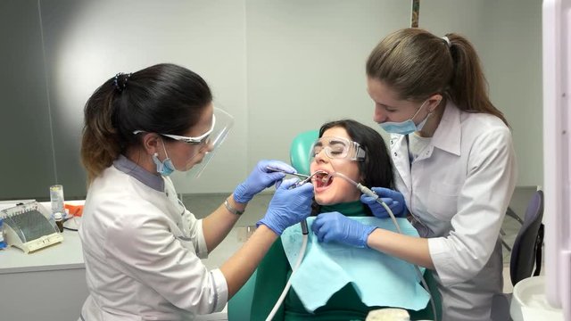 Patient with two dental doctors. Procedure at dentist office. Therapy and treatment of teeth.