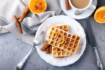Delicious cinnamon waffles with orange zest on table