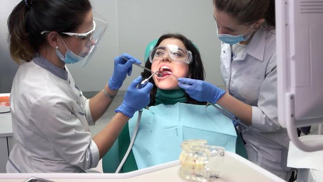 Two dental doctors at work. Female dentist using water syringe.