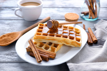 Delicious cinnamon waffles with honey on table