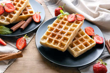 Delicious cinnamon waffles with strawberry on table