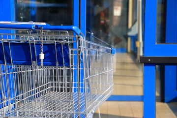 Blauer Einkaufswagen vor Ladentür - 163191299