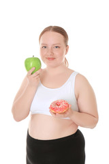 Overweight young woman with apple and donut on white background. Diet concept