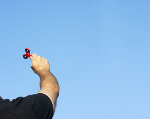 Fidget spinner in man hand on blue sky