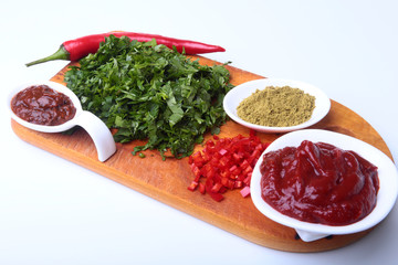 Fresh green cilantro, coriander leaves, tomato paste, chili pepper and spices on a wooden board. Ingredients for meat sauce.