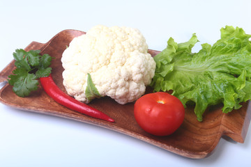 fresh cauliflower, tomato, salad leaves and other vegetables on wooden board. Ready for cooking. Vegetarian food.