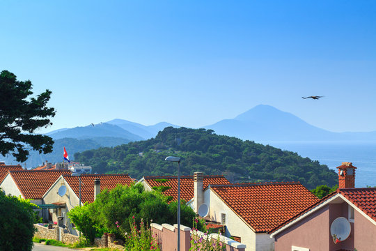 Traditional european Mediterranean architectural style, streets & houses with terracotta roofs, surrounded by cypress, palm, olive, pine trees, on coast azure sea. Location of the prestigious estates