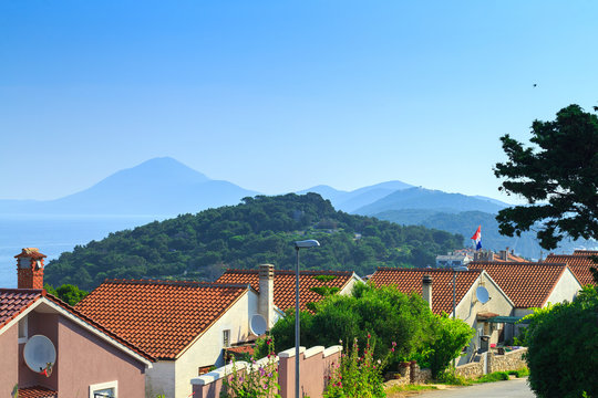 Traditional european Mediterranean architectural style, streets & houses with terracotta roofs, surrounded by cypress, palm, olive, pine trees, on coast azure sea. Location of the prestigious estates