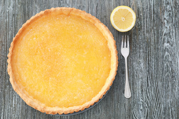Tasty lemon pie with fork on wooden table