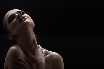 Black and white shot of woman posing sensually holding head up on black background