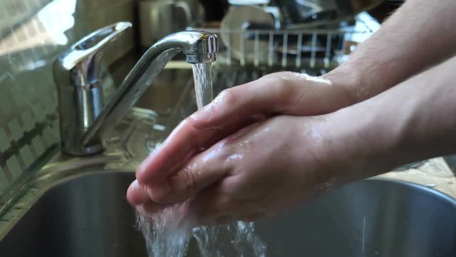 Anonymous male washing hands in kitchen sink, food hygiene 