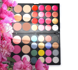 Composition of beautiful peony flowers and palette with eye shadows on light background