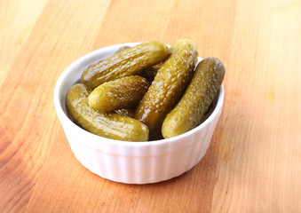 Bowl with pickled gherkins, cucumbers on wooden background close up. Pickles.