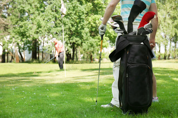 Young men playing golf on course in sunny day