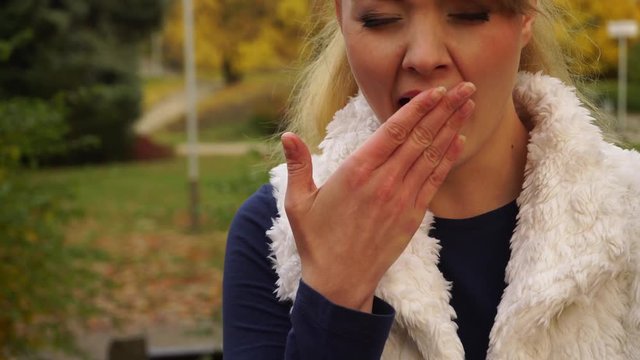 Tired sad woman in autumnal park yawning. Health balance sleep deprivation or seasonal depression. Female student or worker with lack of slumber 4K ProRes HQ codec