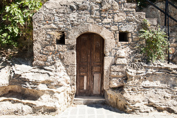 Old wooden door to a stone basement in a Greek house.