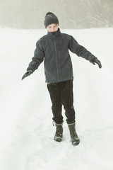 Fototapeta na wymiar Calm boy walking in a path during snowstorm
