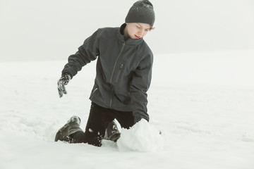 Fototapeta na wymiar Teenager creating a snowball outside