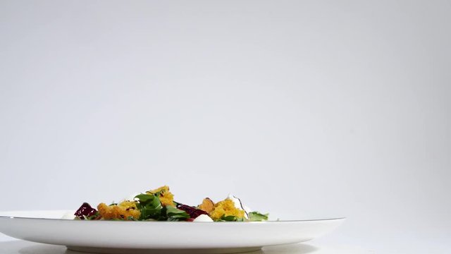 Italian Roast Beet Salad. Salad of roasted beets with goat cheese and pine nuts on white dish isolated on a white background. Tagliatelle with beet and cheese on plate, soft focus