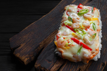 Tasty appetizing asian food. Delicious japanese rice pizza with shrimps served on rustic wooden table