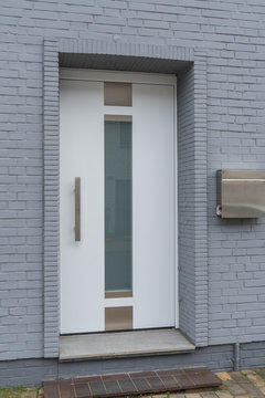 Moderne weiße Haustür mit grauer Fassade