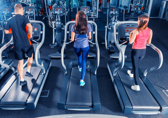 Rear view of group of fit friends exercising on a treadmill