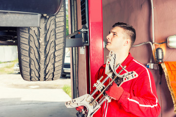 Fototapeta na wymiar Young motor mechanic holding a piece of equipment in an automotive workshop