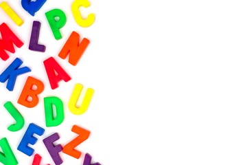 Side border of colorful toy magnetic alphabet letters over a white background